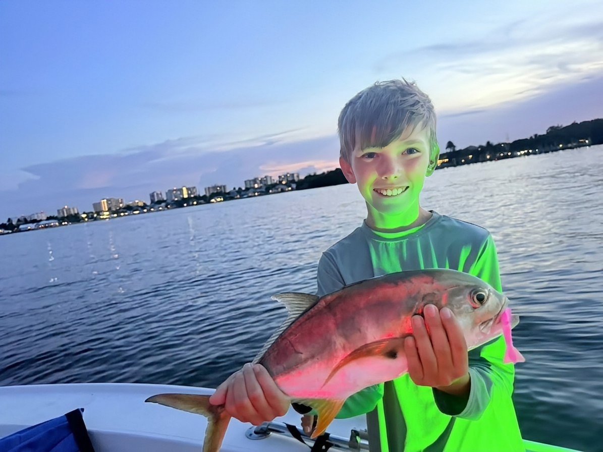 Young angler proudly holding his catch on the water